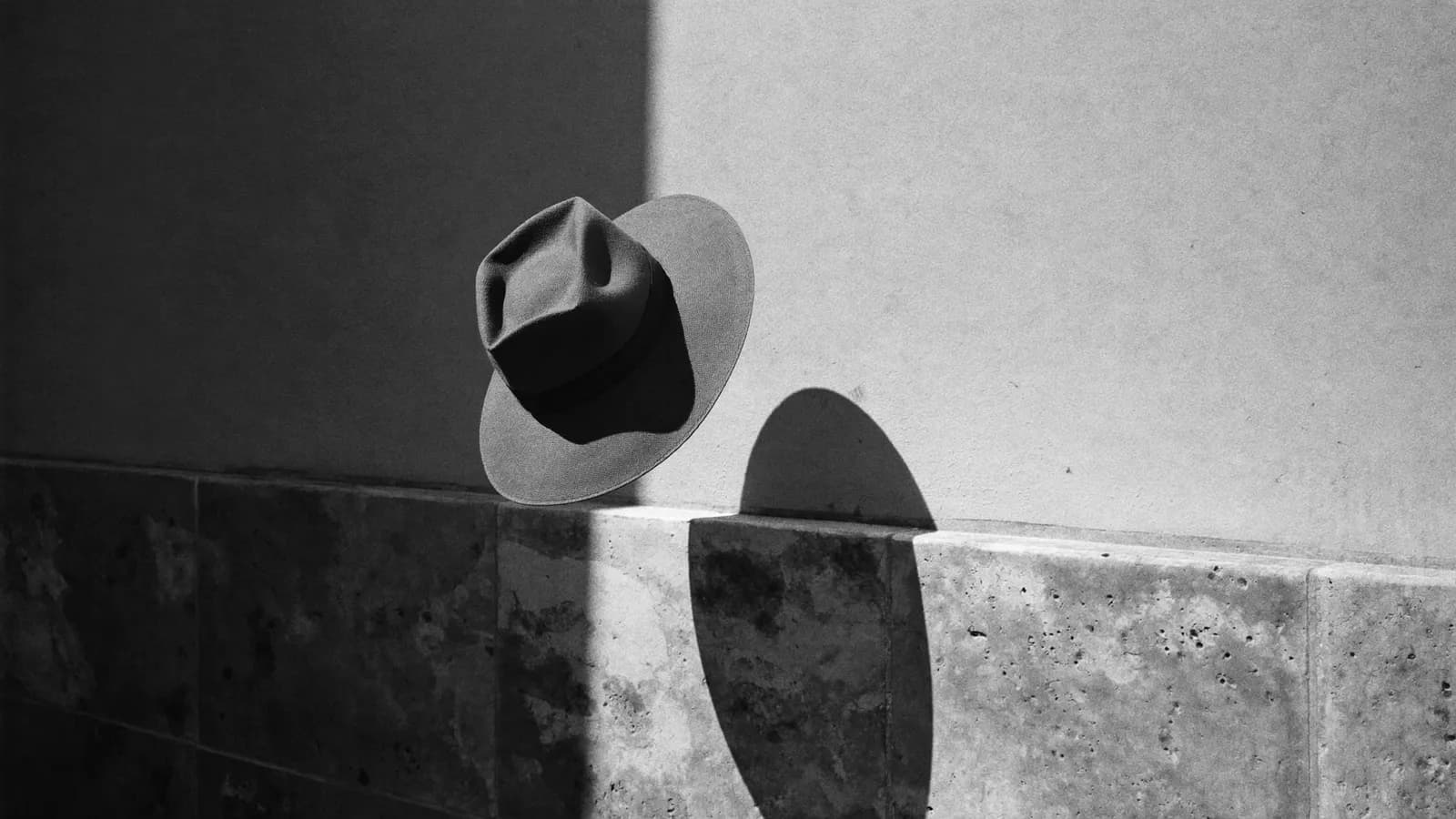 The sharp shadow of a wide-brimmed hat on a limestone wall in strong Maltese sun