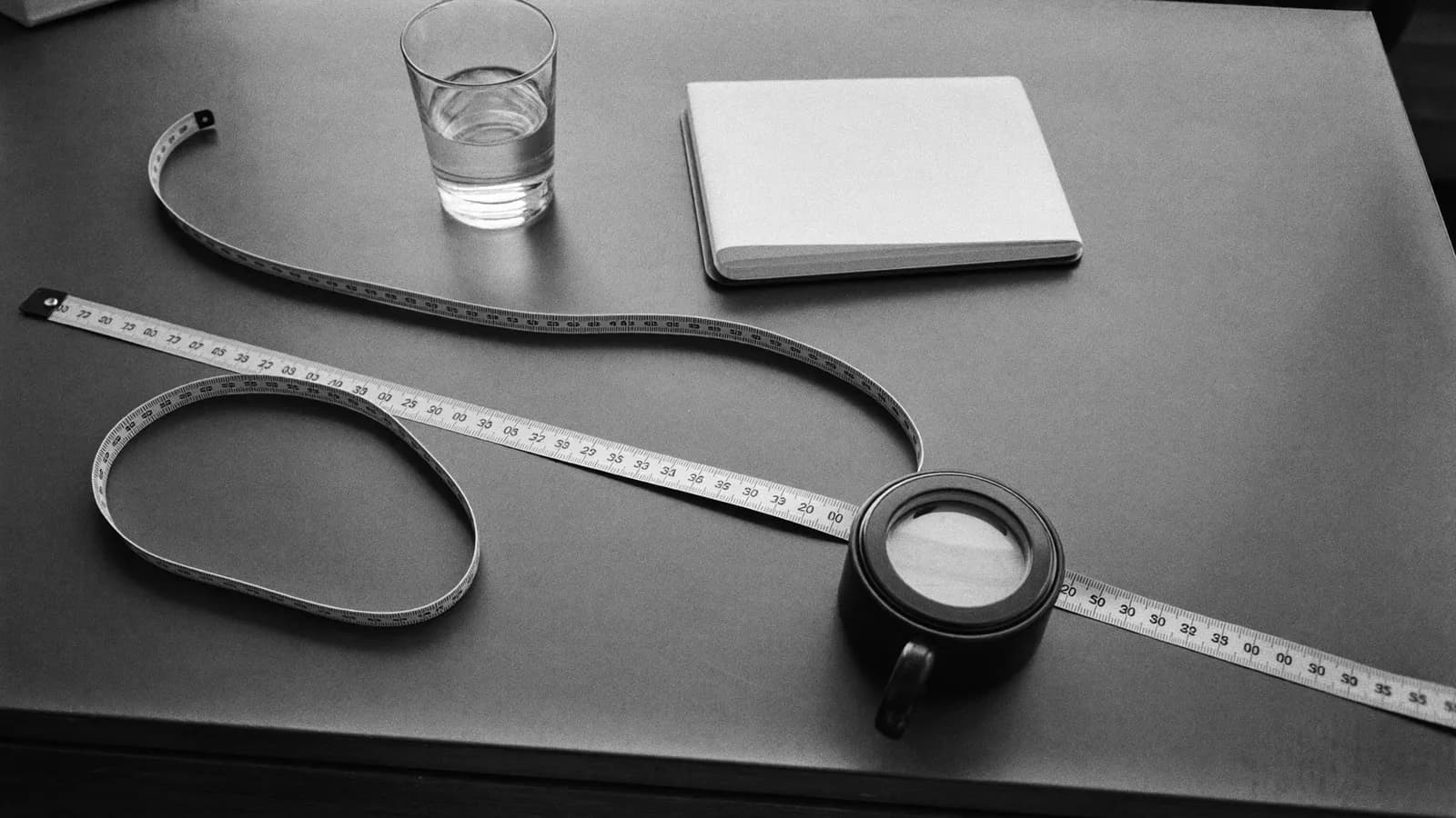 A tape measure, a glass of water and a notebook on a clinic desk